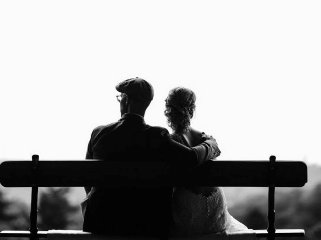 Man en vrouw zitten op een bankje samen, We zien ze van de achterkant.